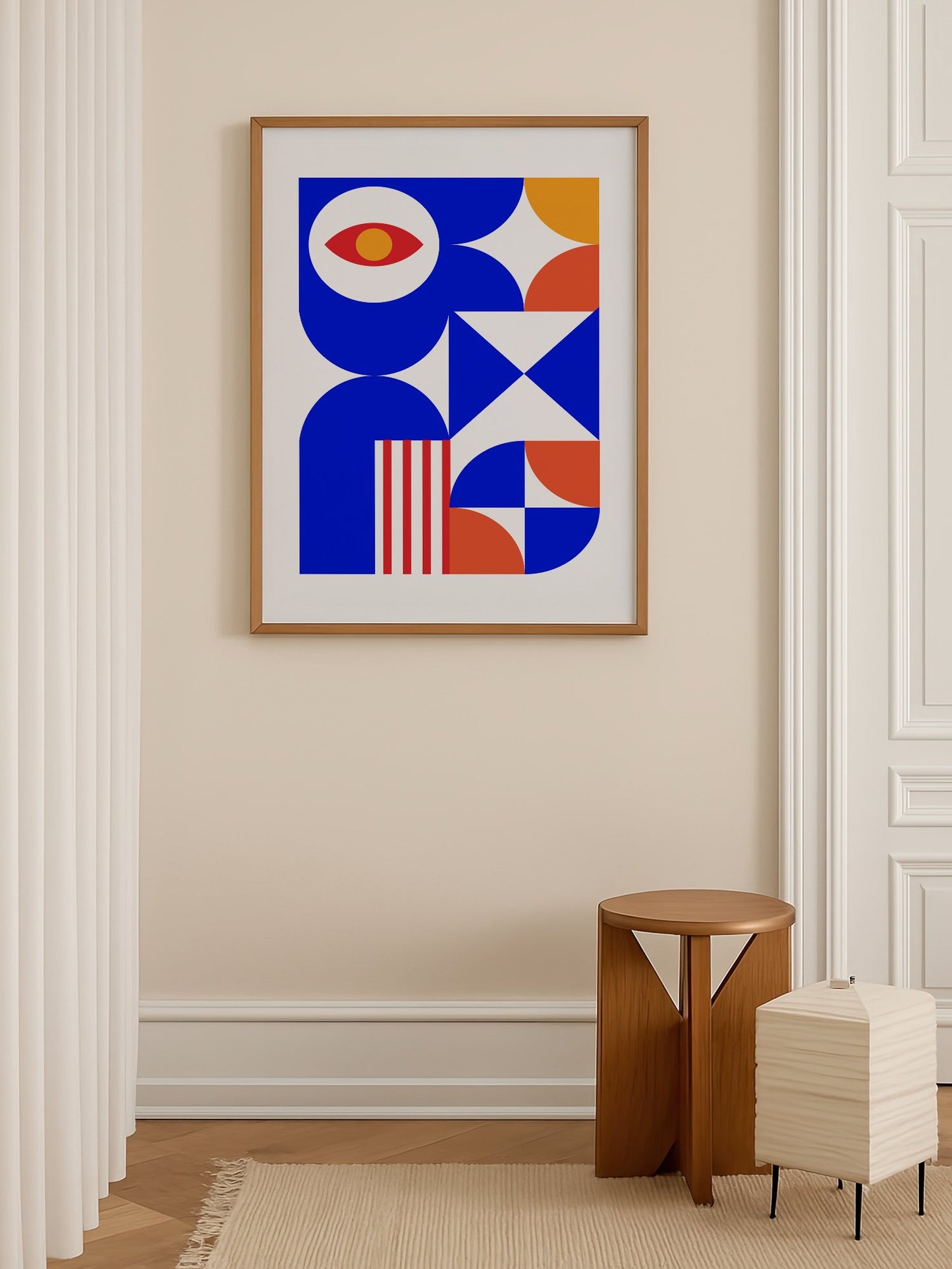 Geometric abstract art print with red eye motif, blue background, coral and, shown in minimalist home office space