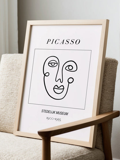 Abstract Picasso face art print featuring minimalist black line drawing on, displayed in modern living room setting
