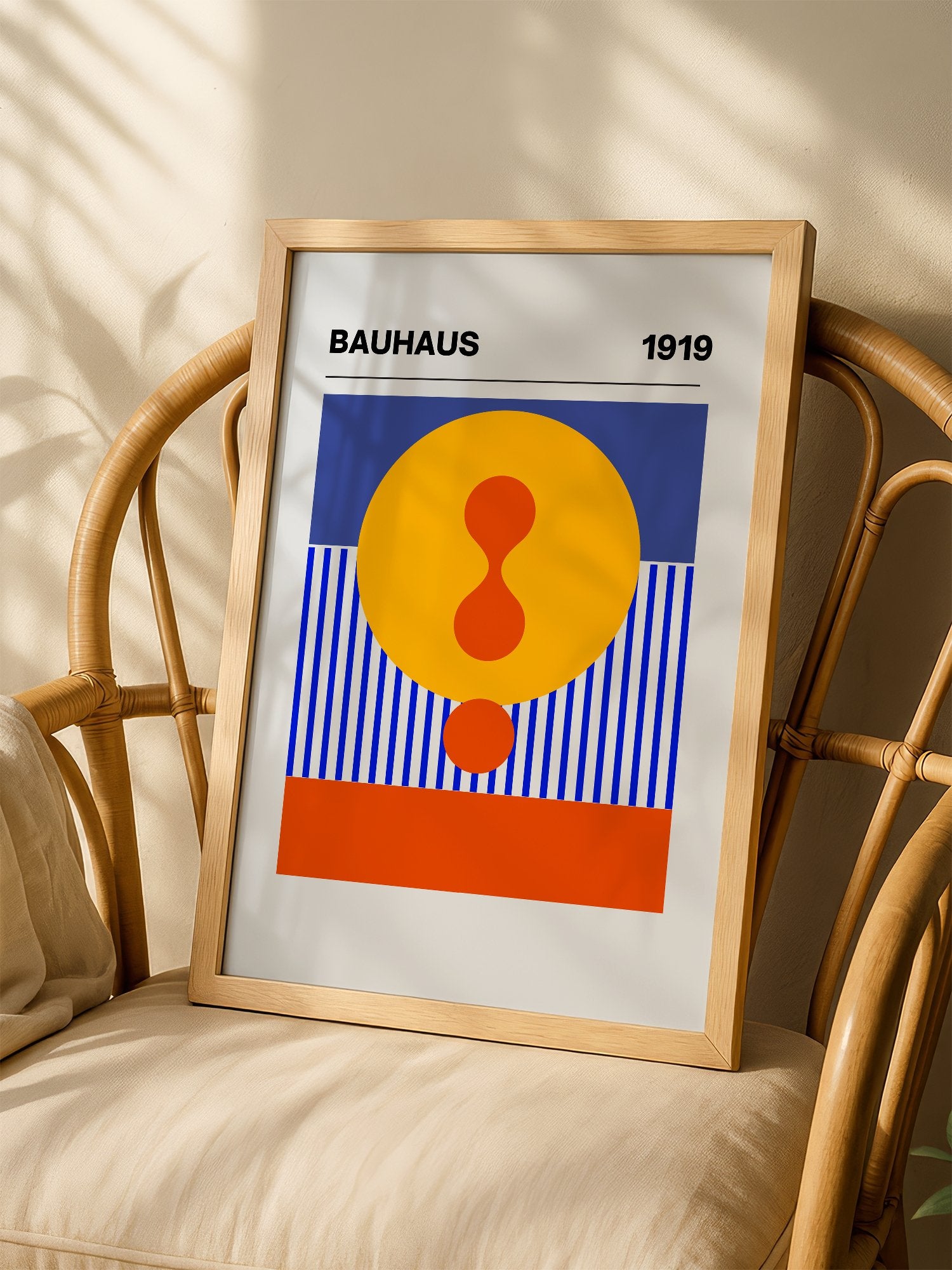 Bauhaus 1919 geometric poster featuring yellow circle with red hourglass shape, shown in minimalist home office space