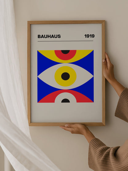 Bauhaus 1919 geometric poster with three stacked eye shapes in yellow red and, hanging in contemporary bedroom interior