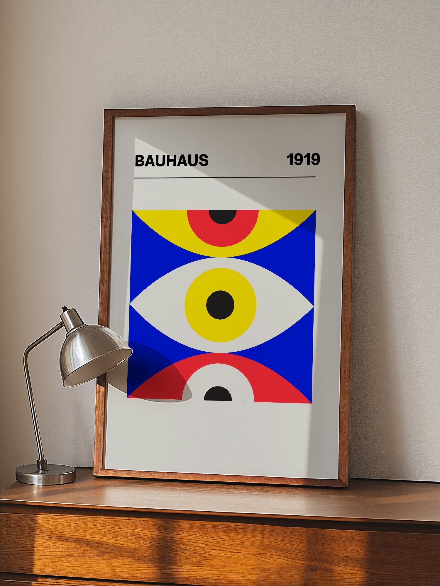 Bauhaus 1919 geometric poster with three stacked eye shapes in yellow red and, displayed in modern living room setting