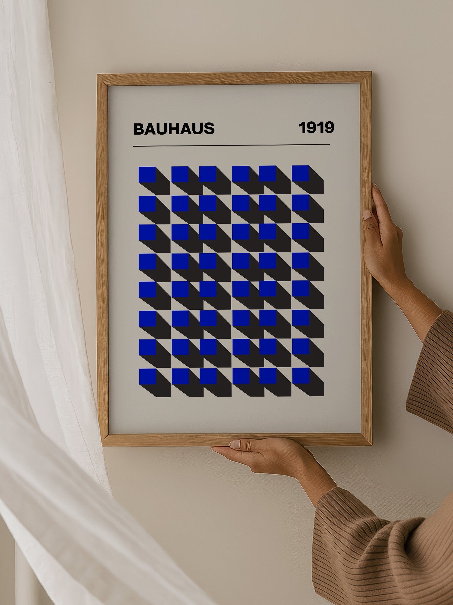 Bauhaus 1919 geometric poster featuring blue isometric cubes arranged in grid, hanging in contemporary bedroom interior