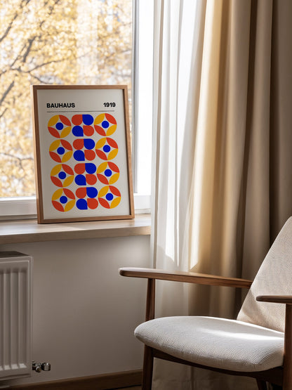Bauhaus 1919 geometric poster featuring circular medallions in blue red yellow, mounted in bright gallery wall arrangement