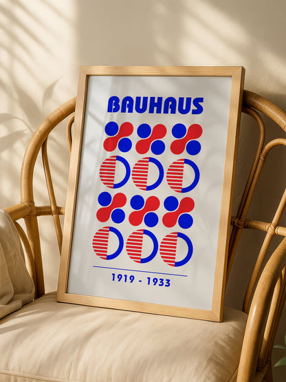 Bauhaus geometric poster featuring blue and red circles and semicircles in grid, shown in minimalist home office space