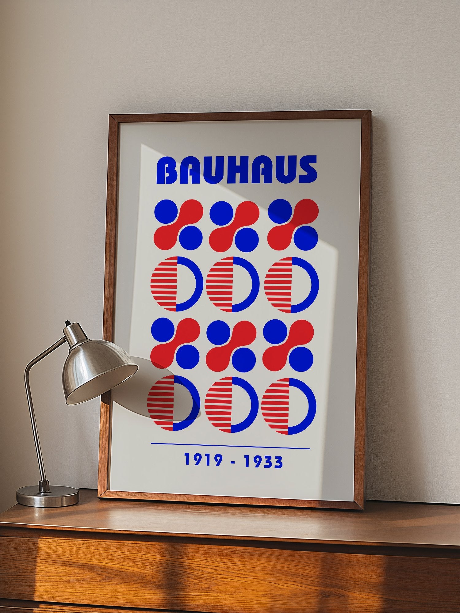 Bauhaus geometric poster featuring blue and red circles and semicircles in grid, displayed in modern living room setting