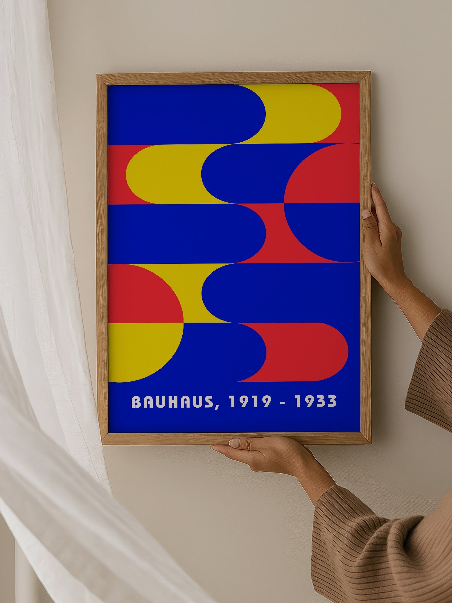 Bauhaus geometric abstract poster with interlocking blue yellow and red shapes, hanging in contemporary bedroom interior