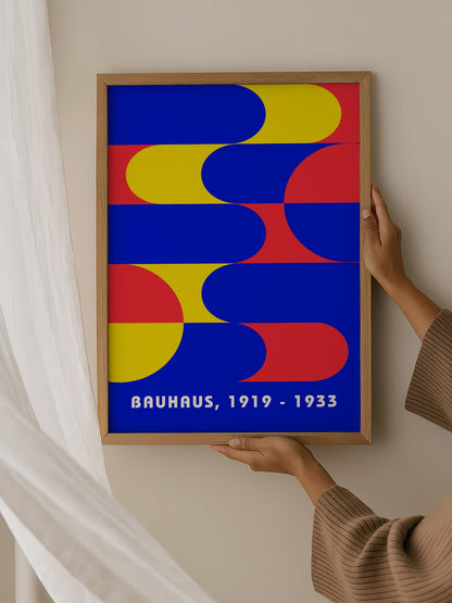 Bauhaus geometric abstract poster with interlocking blue yellow and red shapes, hanging in contemporary bedroom interior
