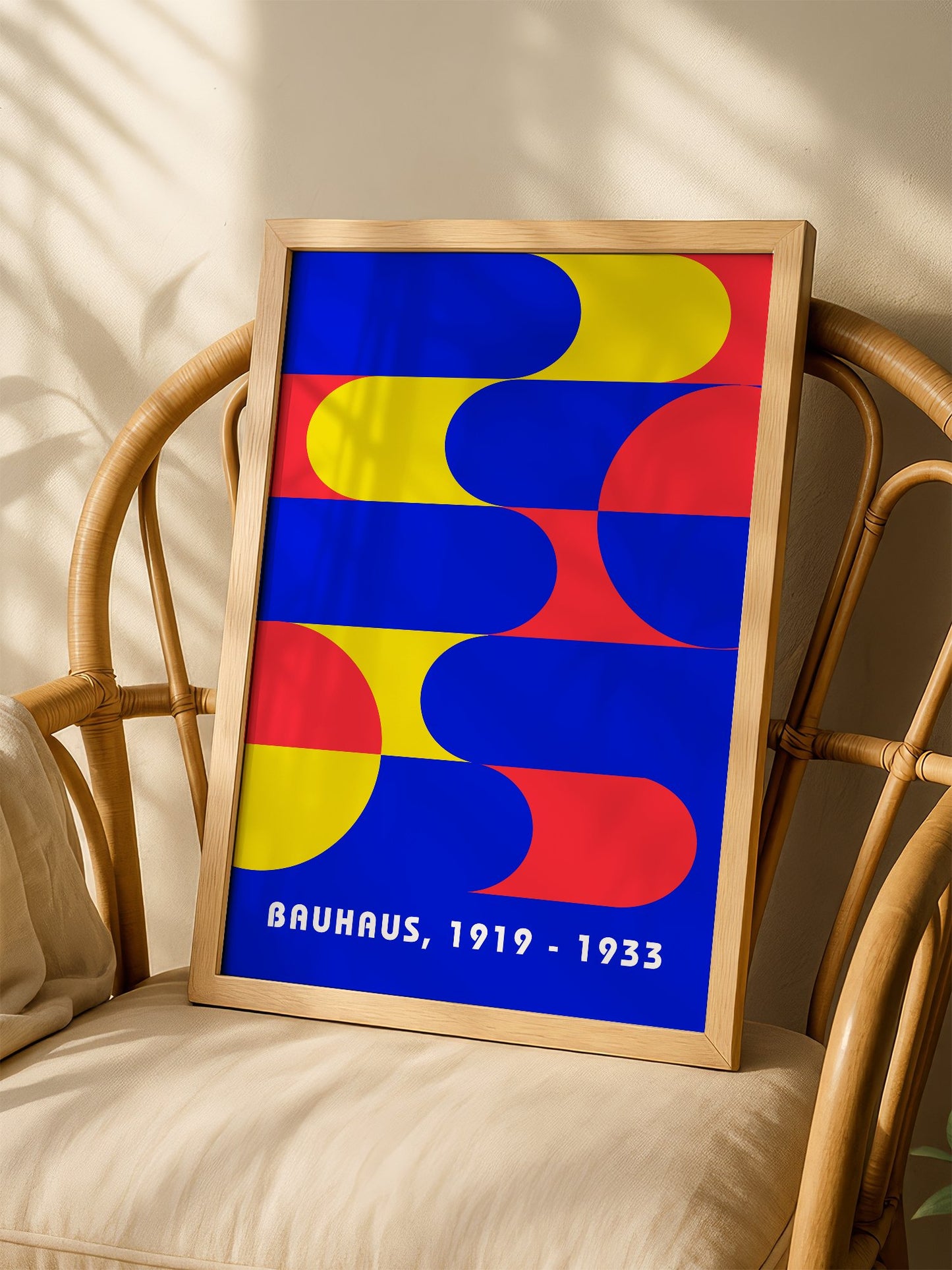 Bauhaus geometric abstract poster with interlocking blue yellow and red shapes, shown in minimalist home office space