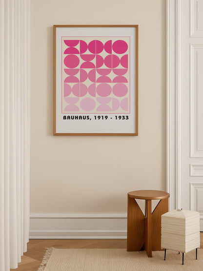Bauhaus geometric poster featuring pink circles and semicircles in gradient, shown in minimalist home office space