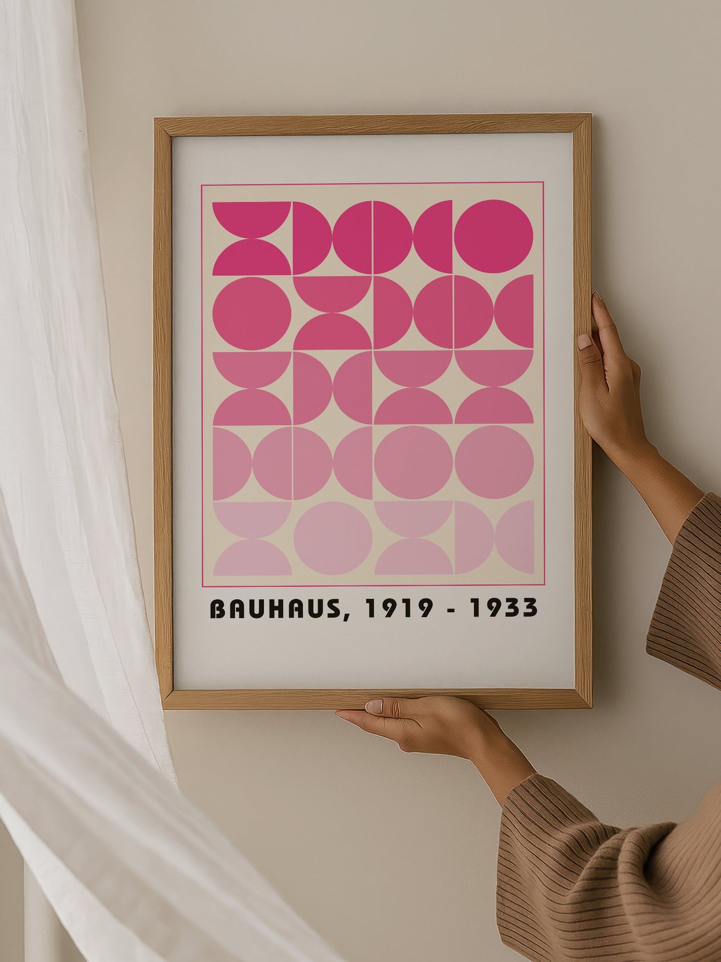 Bauhaus geometric poster featuring pink circles and semicircles in gradient, hanging in contemporary bedroom interior