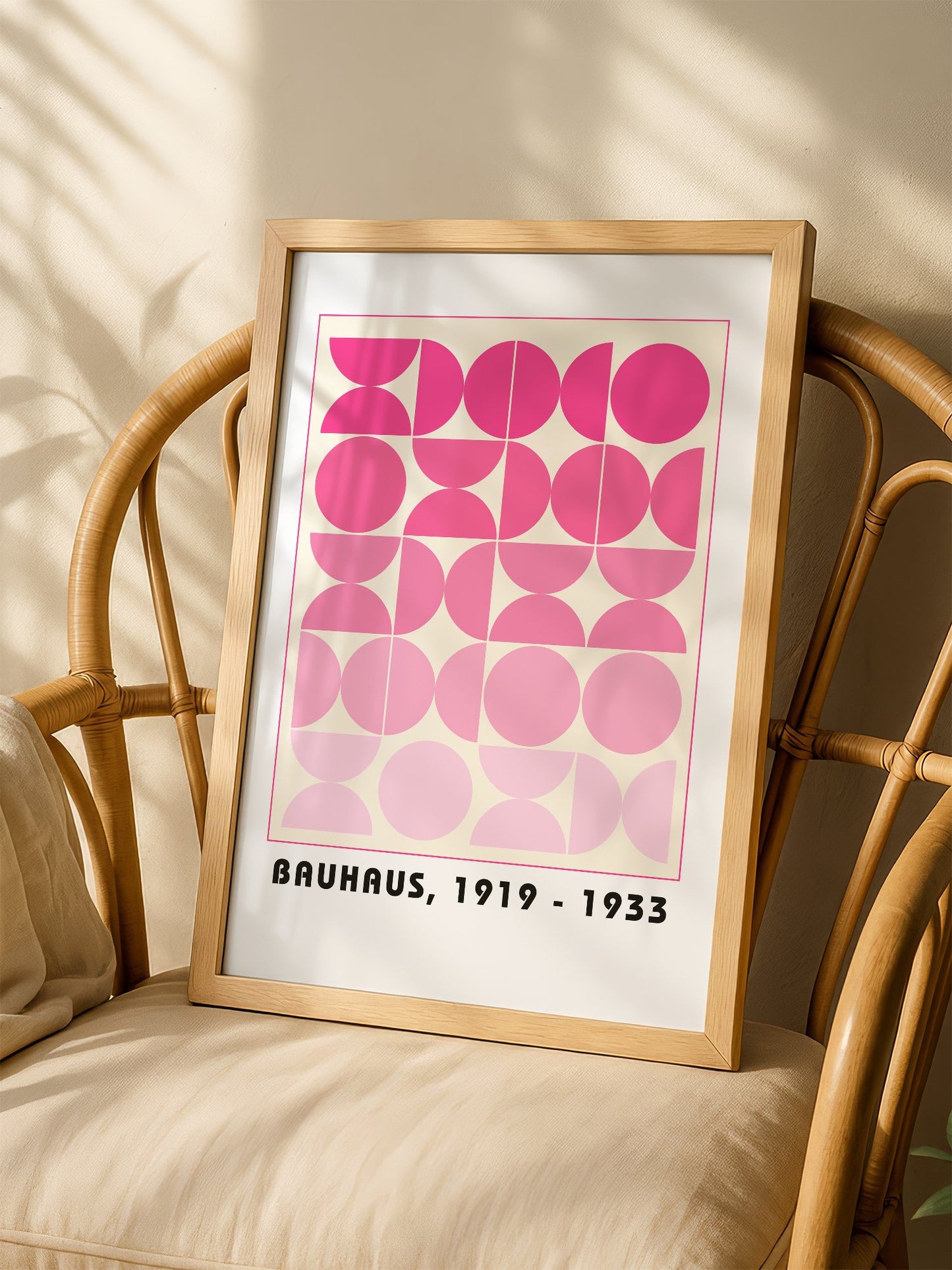 Bauhaus geometric poster featuring pink circles and semicircles in gradient, shown in minimalist home office space