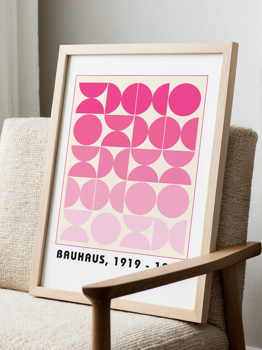 Bauhaus geometric poster featuring pink circles and semicircles in gradient, displayed in modern living room setting