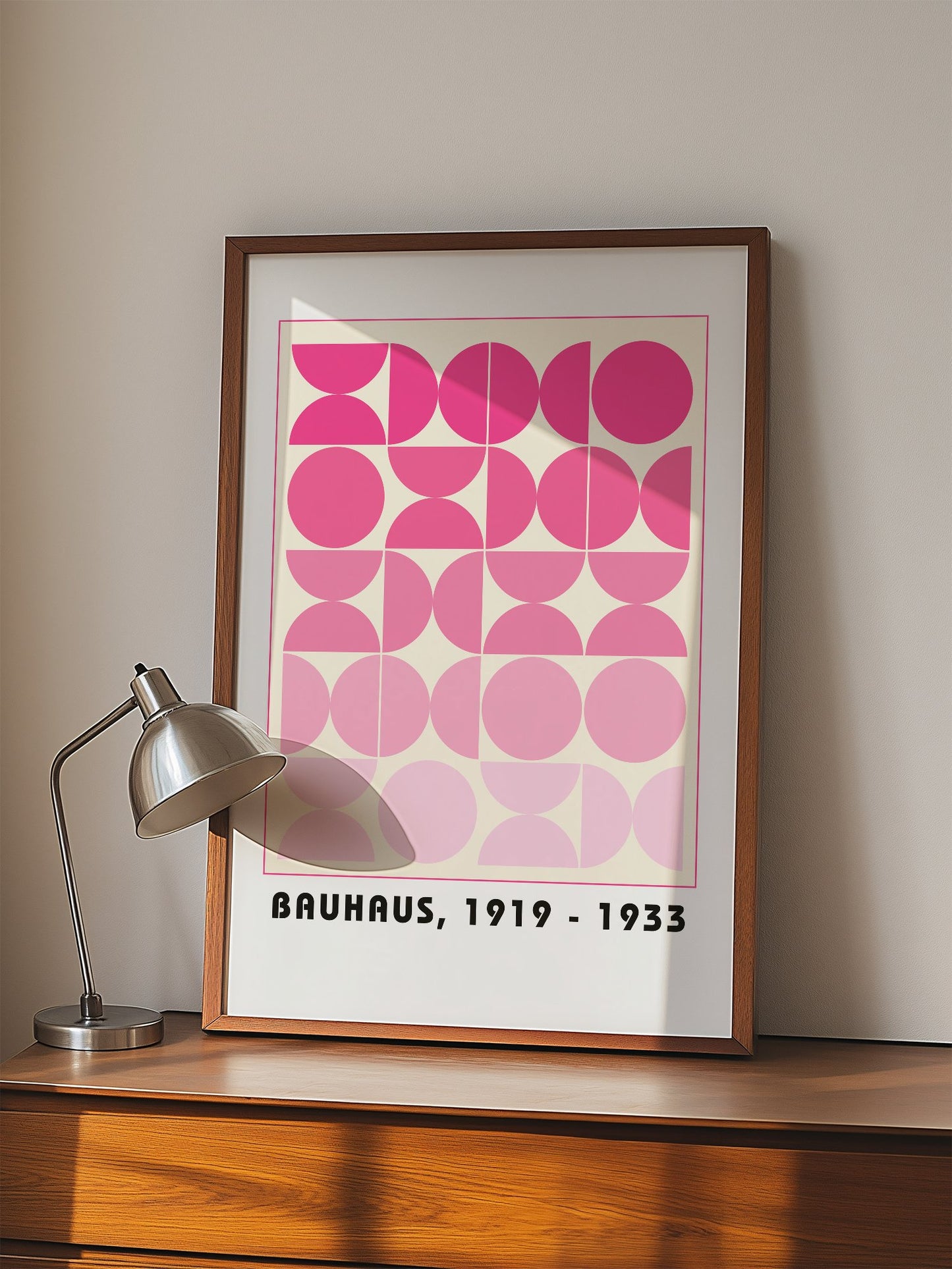 Bauhaus geometric poster featuring pink circles and semicircles in gradient, displayed in modern living room setting