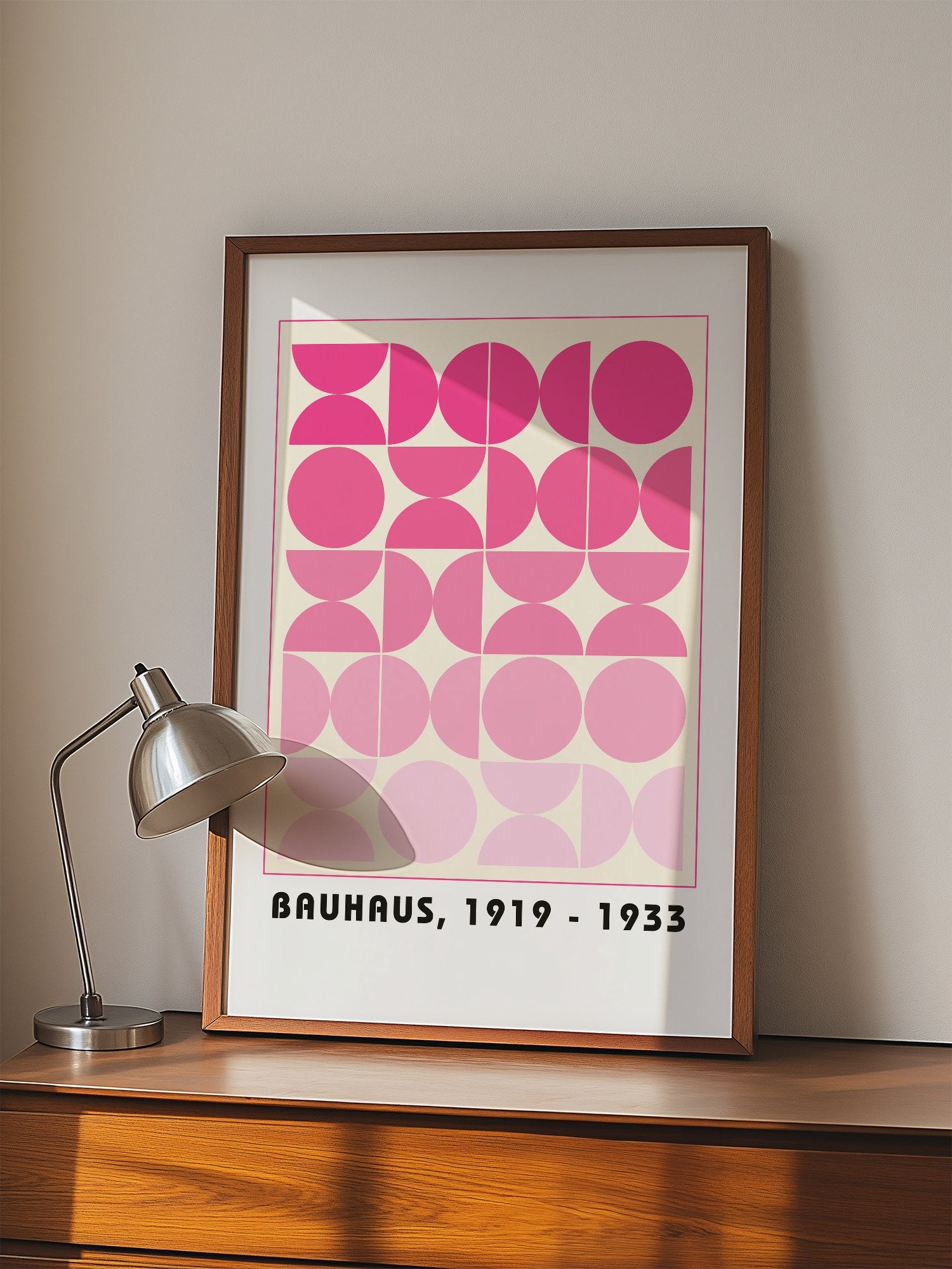 Bauhaus geometric poster featuring pink circles and semicircles in gradient, displayed in modern living room setting