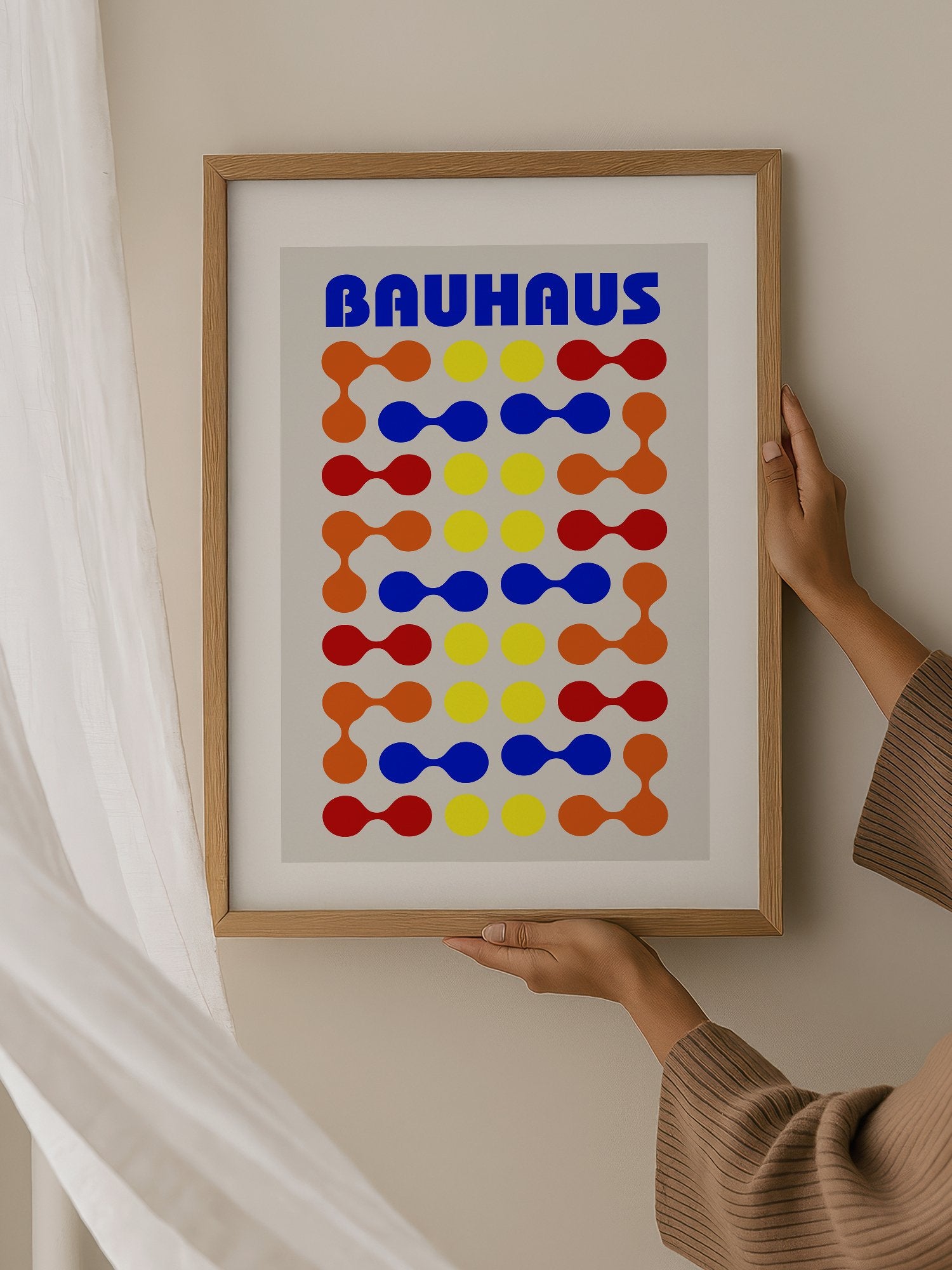 Bauhaus poster with bold blue typography and geometric grid pattern of circles, hanging in contemporary bedroom interior