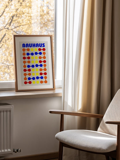 Bauhaus poster with bold blue typography and geometric grid pattern of circles, mounted in bright gallery wall arrangement