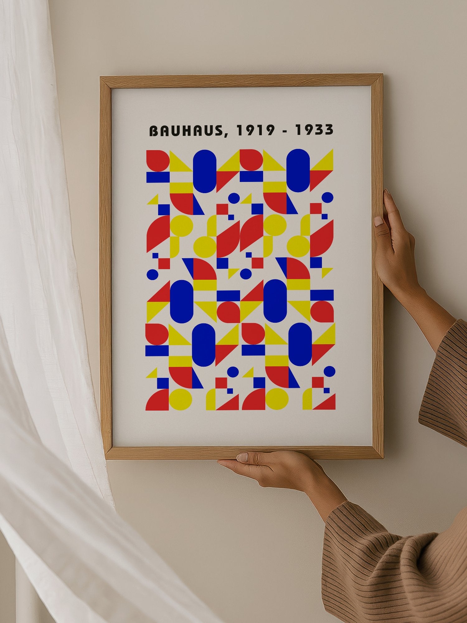 Bauhaus geometric poster with red circles, yellow triangles, and blue ovals in, hanging in contemporary bedroom interior