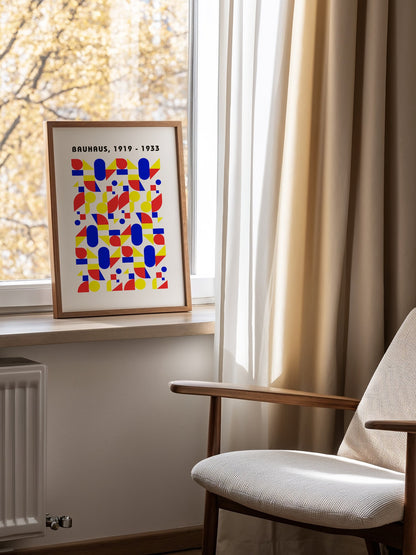 Bauhaus geometric poster with red circles, yellow triangles, and blue ovals in, mounted in bright gallery wall arrangement