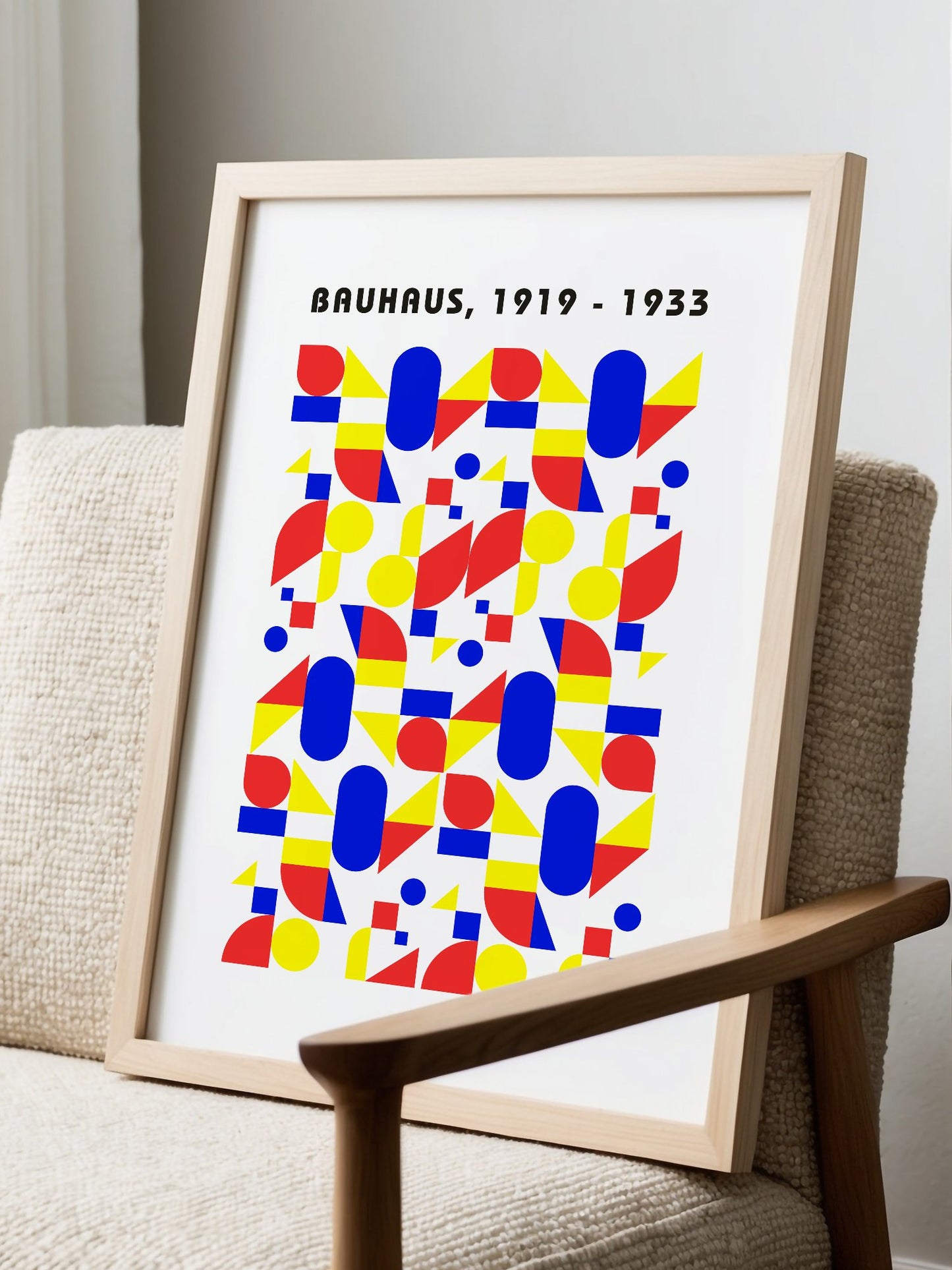 Bauhaus geometric poster with red circles, yellow triangles, and blue ovals in, displayed in modern living room setting