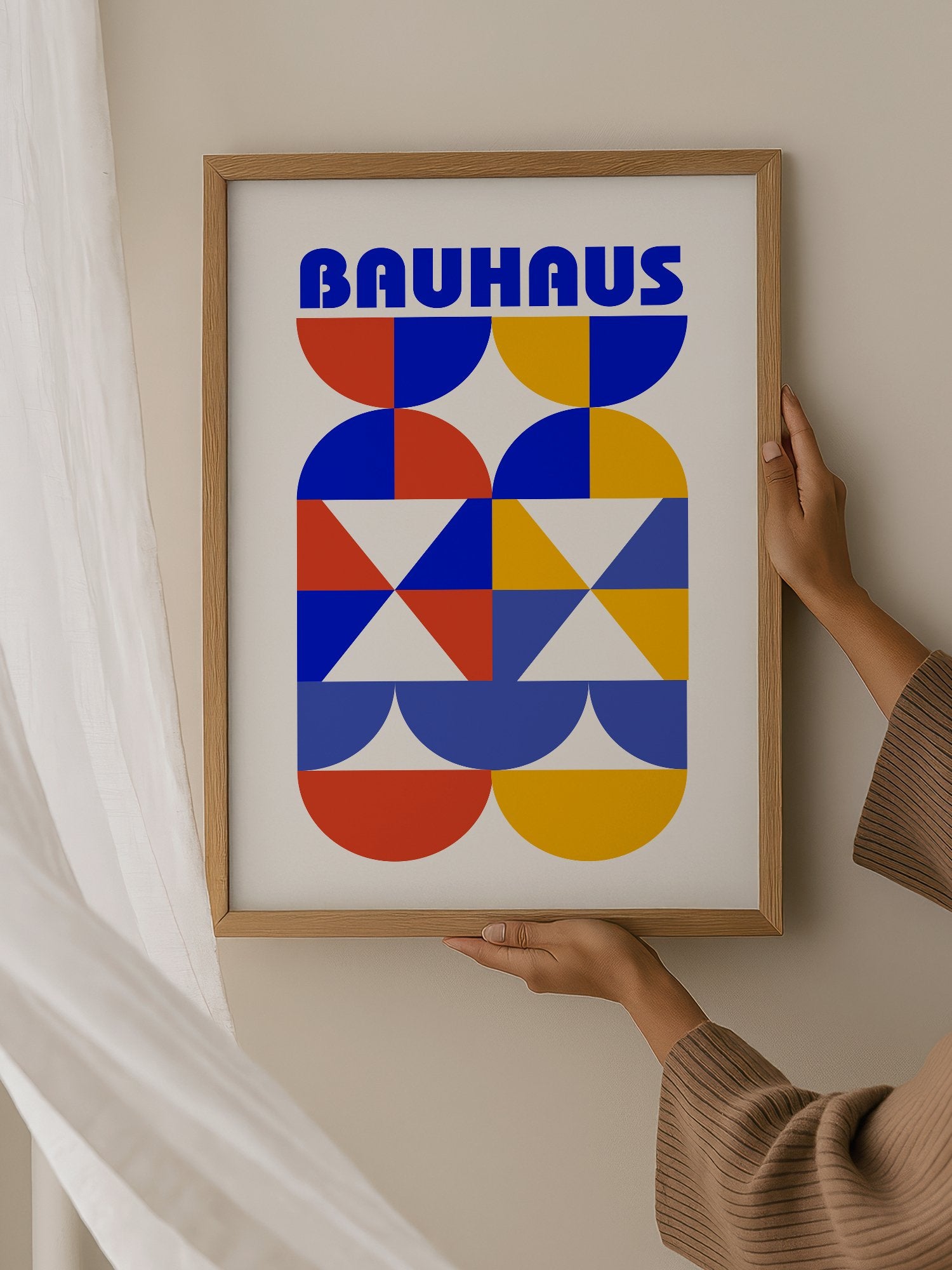 Bauhaus geometric poster featuring bold blue typography above symmetrical, hanging in contemporary bedroom interior
