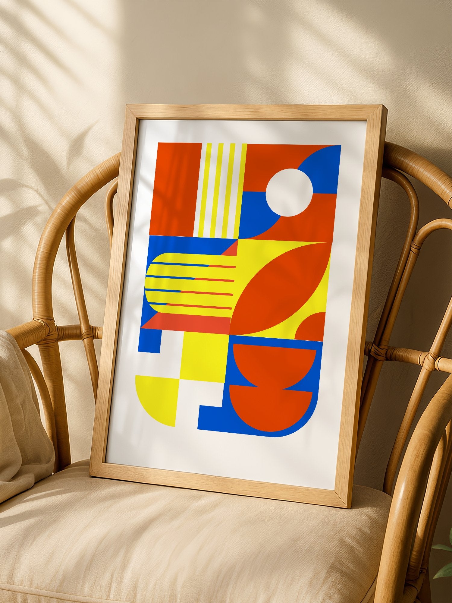 Abstract geometric wall art with interlocking orange, blue and yellow shapes, shown in minimalist home office space