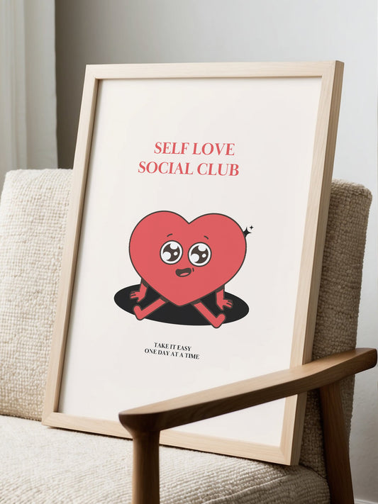Cute pink heart character wall art with 'Self Love Social Club' text, displayed in modern living room setting