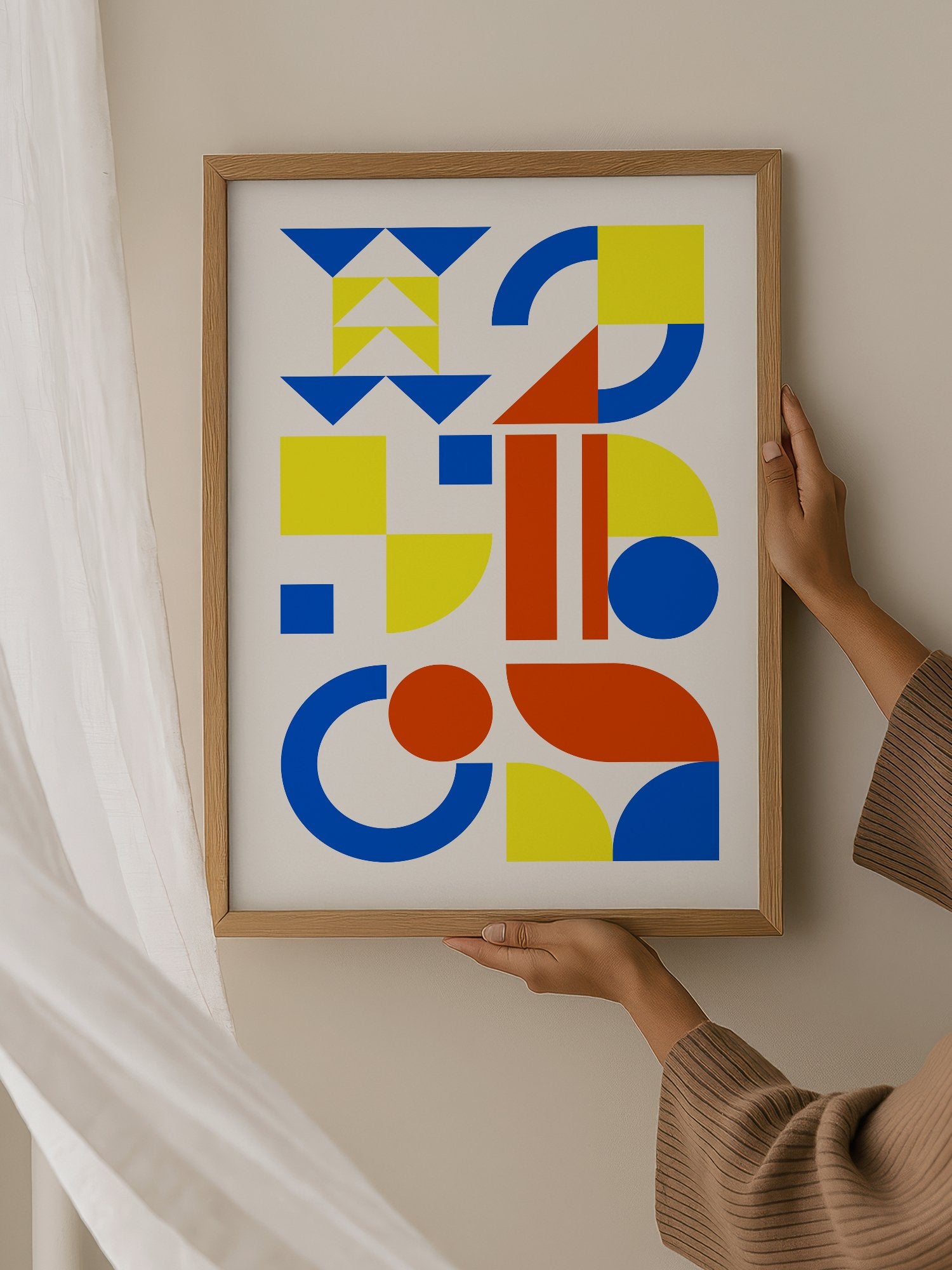 Geometric abstract wall art with blue, yellow and red triangles, circles and, hanging in contemporary bedroom interior