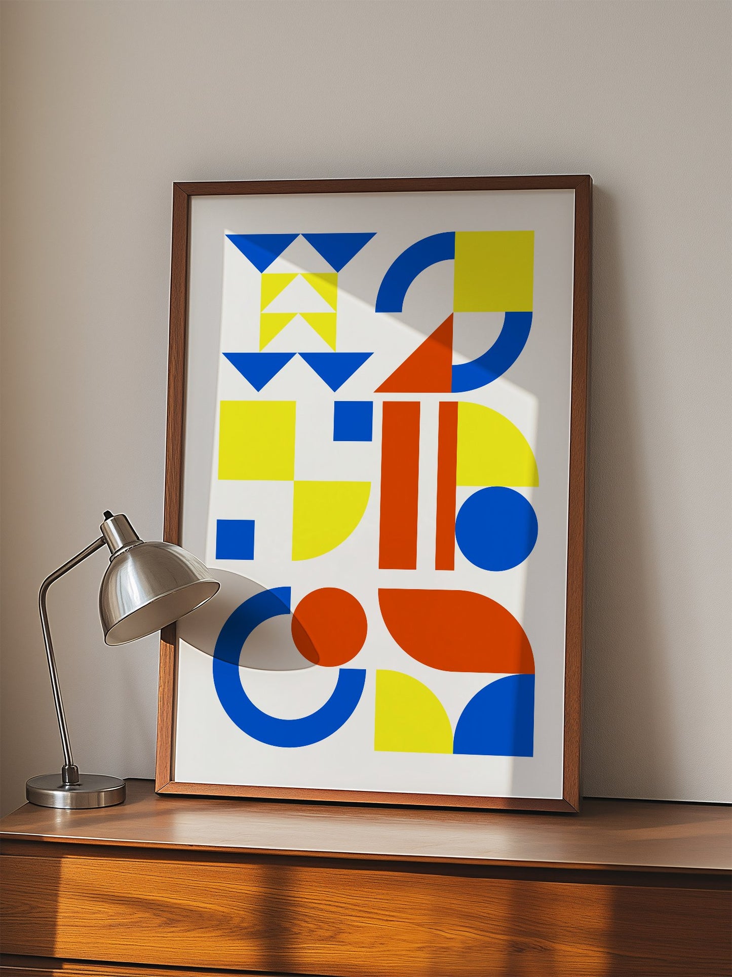 Geometric abstract wall art with blue, yellow and red triangles, circles and, displayed in modern living room setting