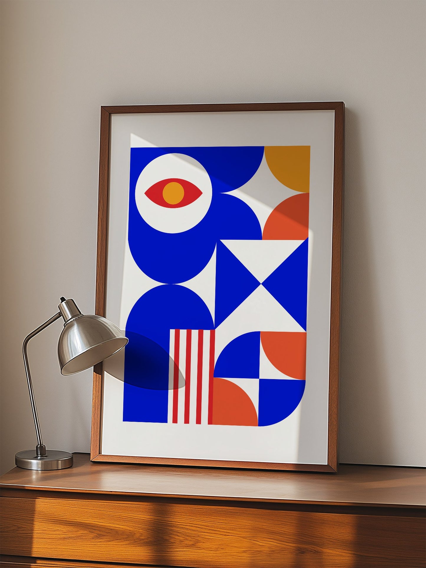 Geometric abstract art print with red eye motif, blue background, coral and, displayed in modern living room setting