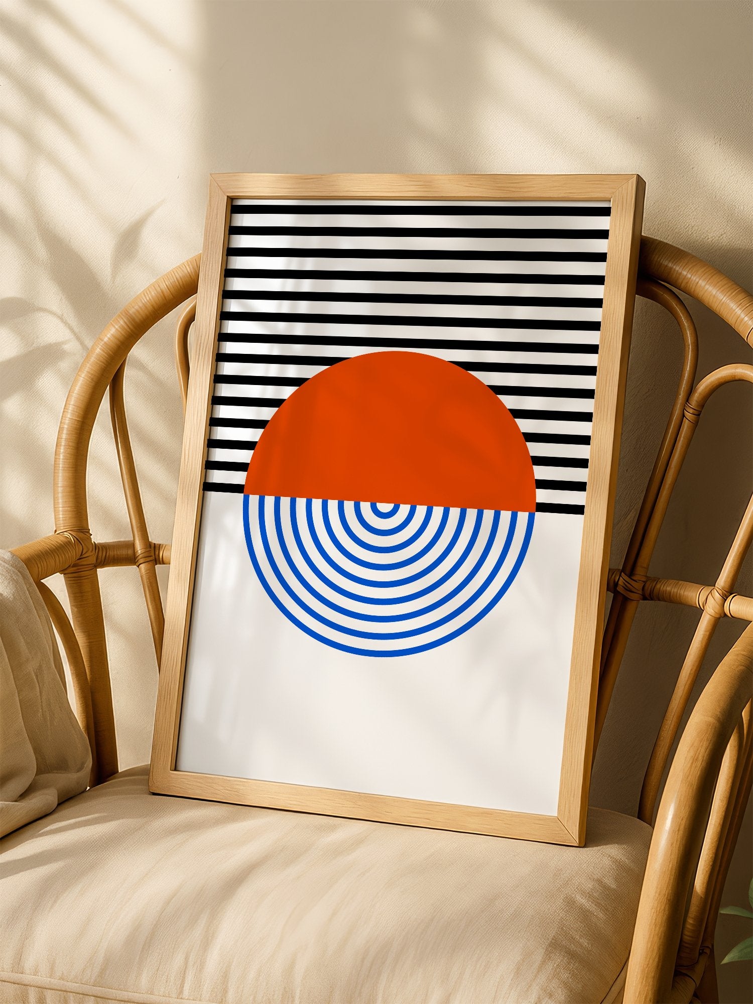 Geometric abstract wall art featuring split circle with orange top and blue, shown in minimalist home office space