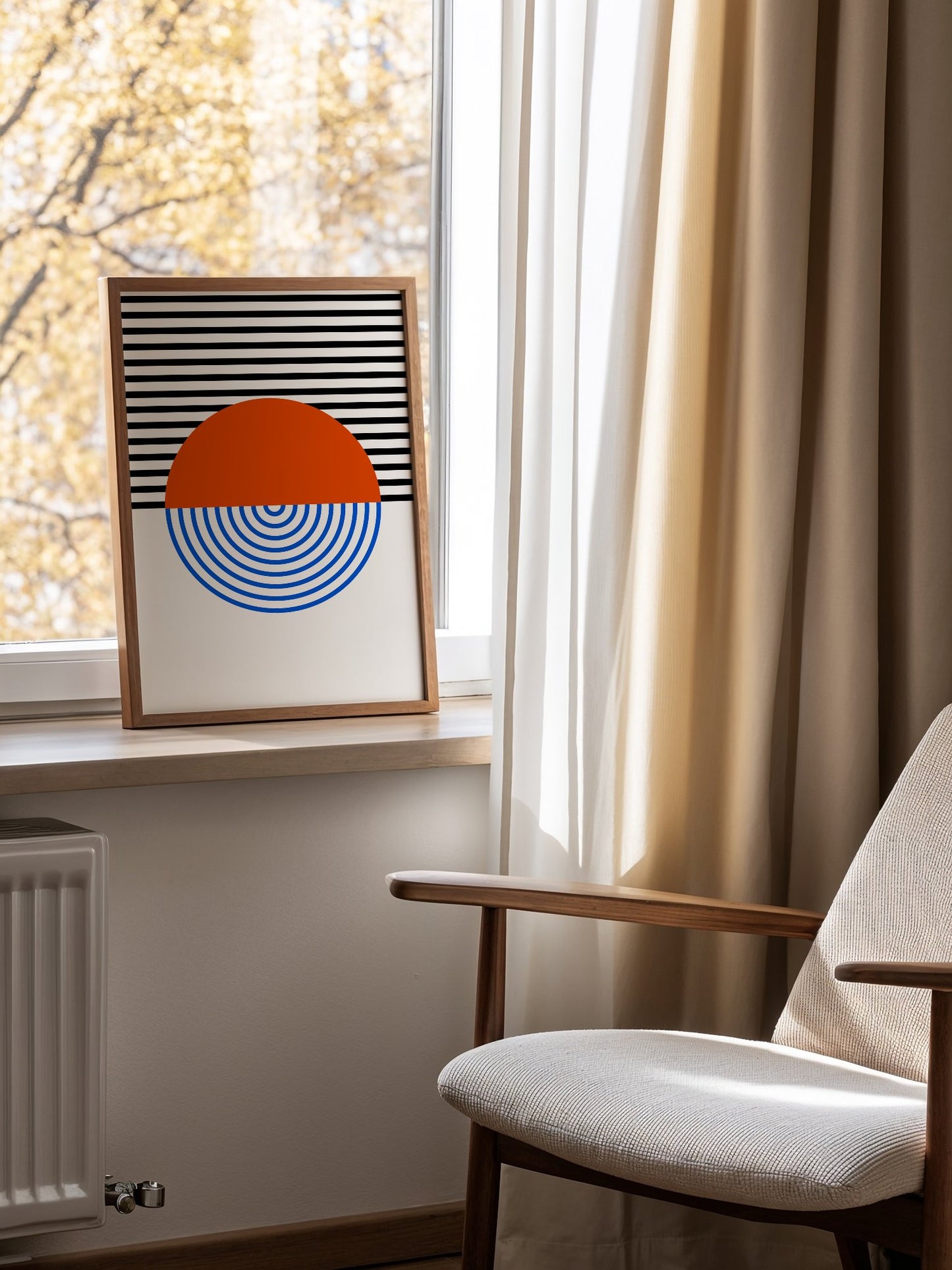 Geometric abstract wall art featuring split circle with orange top and blue, mounted in bright gallery wall arrangement