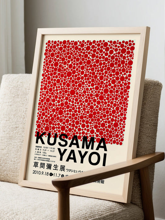 Kusama Yayoi exhibition poster with red polka dots scattered on cream, displayed in modern living room setting